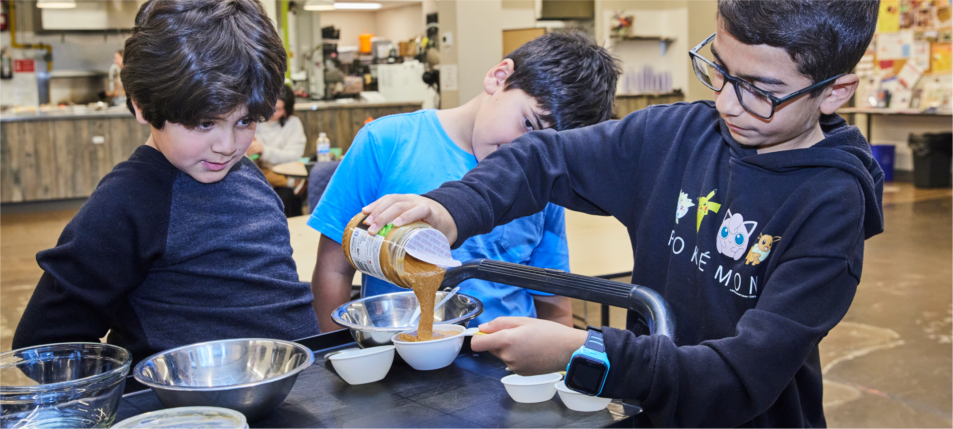 Trois enfants préparent un repas dans un centre communautaire d’alimentation.